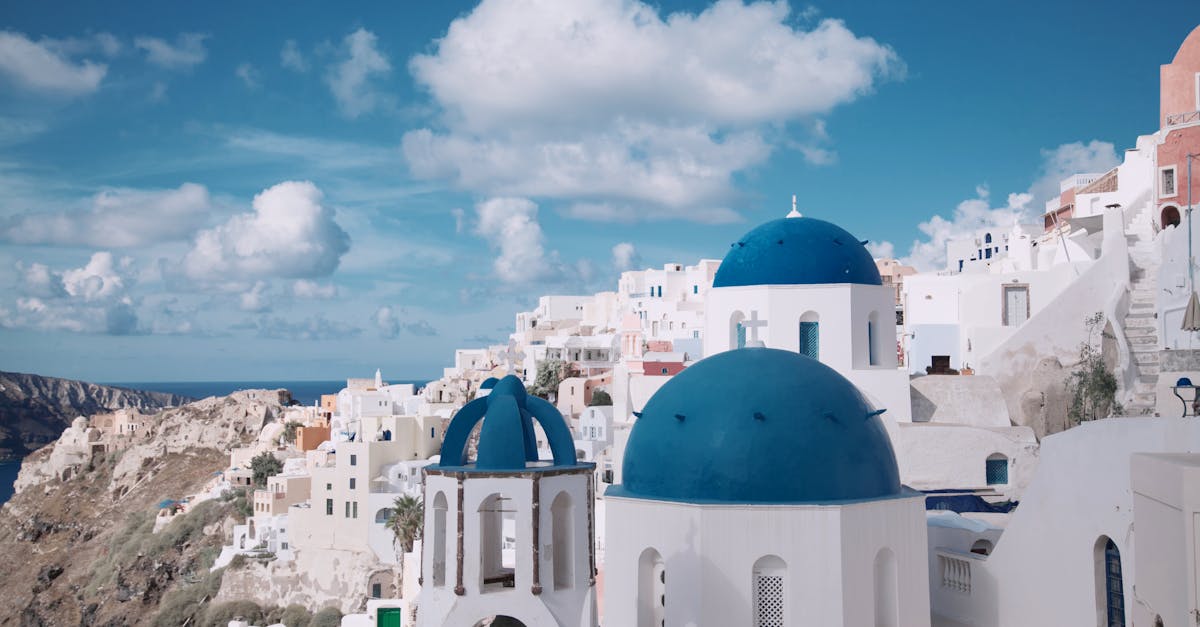 Breathtaking view of Oia's iconic blue-domed churches against a vibrant sky in Santorini, Greece.