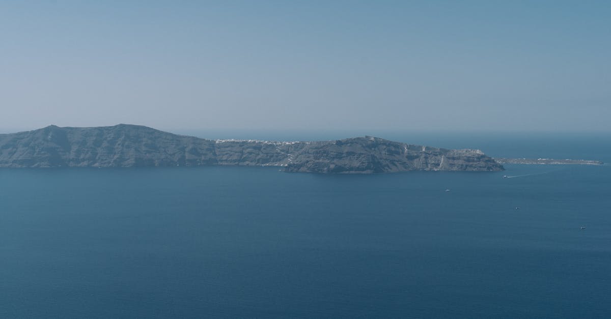Serene aerial view of Santorini island surrounded by crystal blue waters under a clear sky.