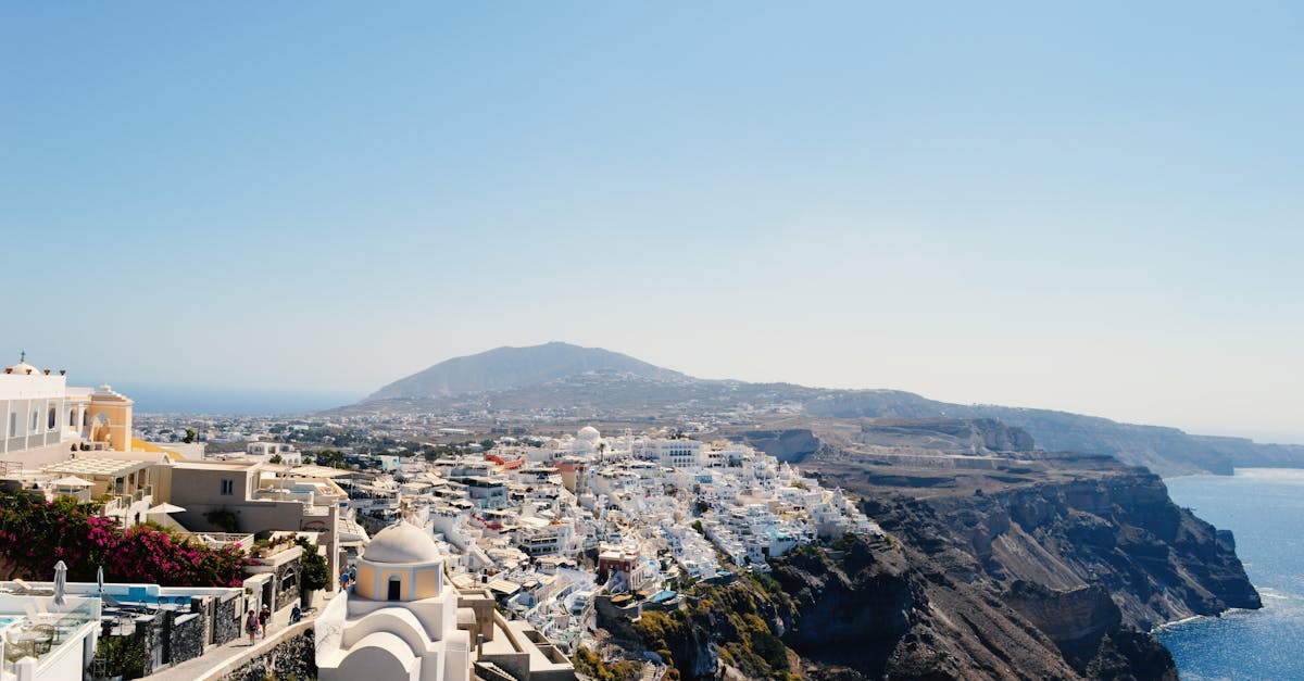 Scenic view of Santorini's iconic whitewashed buildings and coastal cliffs under a clear blue sky.